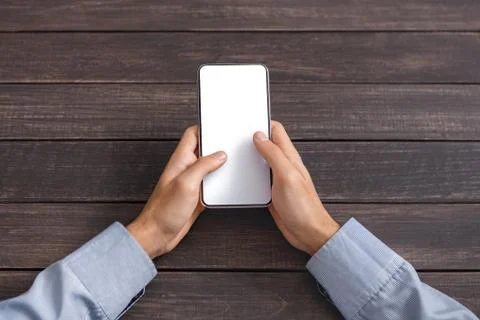 Male hands using smartphone with blank screen over wooden background Stock Photos