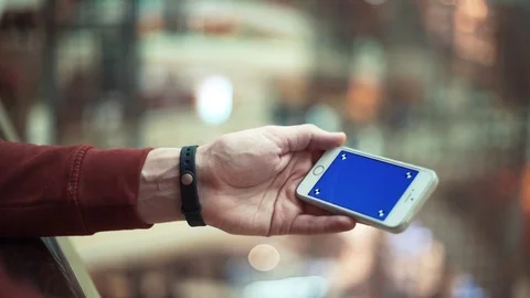 Male hands using smartphone with blue screen in shopping mall Stock Footage 82989615