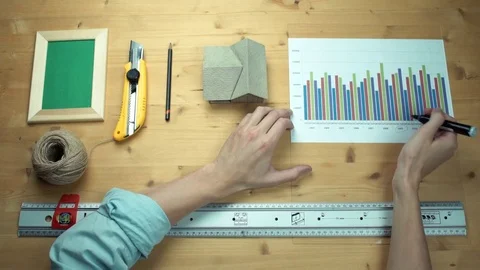 Male hands working with printed graphs making notes with marker at wooden desk. Stock Footage 82901767