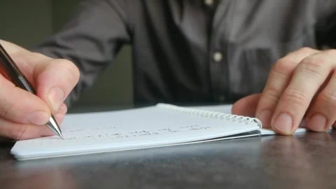 Male hands writing notes in a notebook with a ballpoint pen Vidéo 337892323