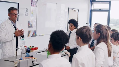 Male High School Tutor Teaching Students Wearing Uniforms In Science Class Stock Footage
