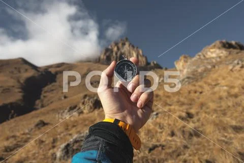 A male Hiker is looking for a direction with a magnetic compass in the mountains Stock Photos