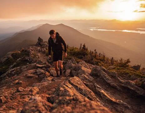 Male hiker walks along Appalachian Trail on Bigelow Mountain at sunset Stock Photos
