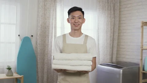 Male housekeeper holding a stack of clean towels Stock Footage 208108274