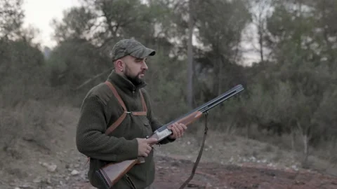 Male hunter holding a gun while standing outdoors in the nature. Video stock 237108822