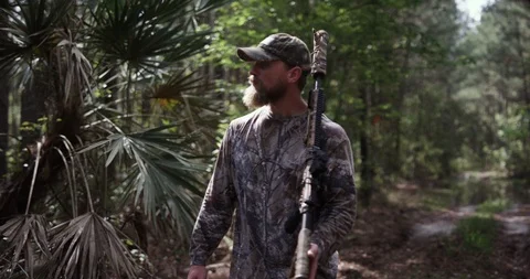 Male hunter walking through a forest with a rifle Stock Footage 107629329