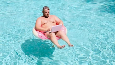 Male with an inflatable ring in the water in the pool works on the computer Stock Footage 113041241