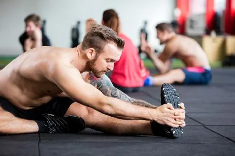 Male Instructor Doing Stretching Exercise On Floor Stock Photos