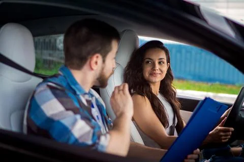 Male instructor explaining rules for young woman during driving school training Stock Photos