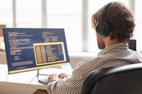 Male IT Developer Using Computer at Desk in Office and Wearing Headphones Stock Photos