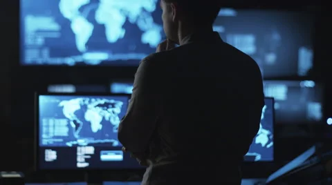 Male IT employee is looking at computer screens with maps and data on display Stock Footage 59378618