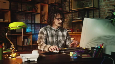Male IT engineer in 90s typing on computer keyboard, creating new program Stock Footage 315456166