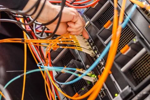 Male IT Engineer Plugging High Speed Fiber Cable In Network Switch Stock Photos