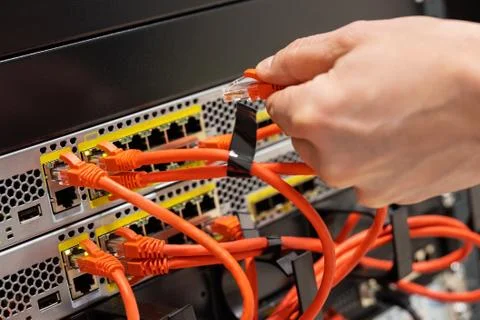 Male IT Engineer Plugging Network Cable In Router in Datacenter Stock Photos
