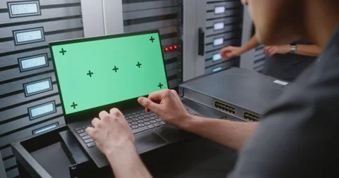 Male IT Engineer Using Laptop with Green Screen Near Server Racks in Data Center Stock Footage 344965875