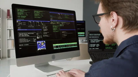 Male IT Programmer Reading Multiple Computer Screens while Coding in Office Stock Footage 330125992