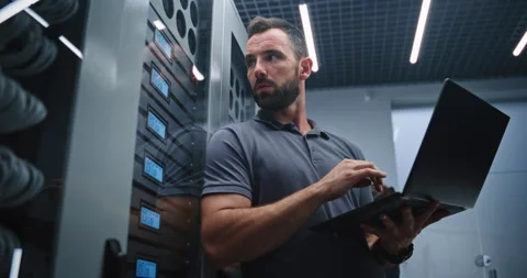 Male IT Specialist Analyzing Server Performance and Checking LED Status Stock Footage 347911098