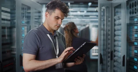 Male IT Specialist Using Tablet while Female Engineer Inspects Server Rack Vídeo Stock 344888711