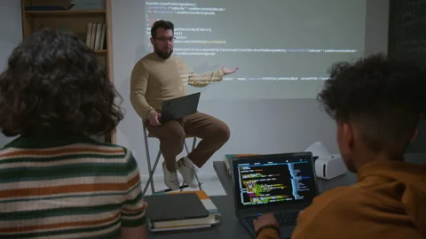 Male IT Teacher Demonstrating Code Projected on Screen to Diverse Students Stock Footage 318719338