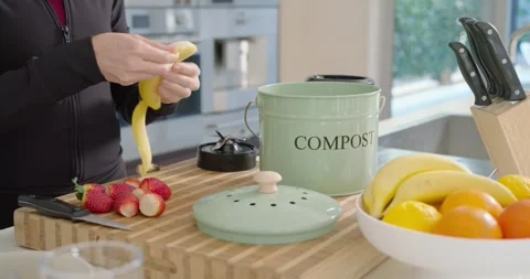 Male in jacket placing compost caddy, peeling, slicing banana on wooden board Vídeos de archivo 341974900