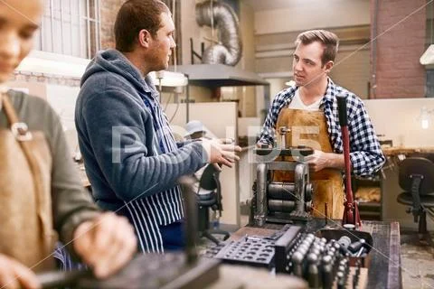 Male jewelers talking and using equipment in workshop Stock Photos