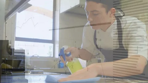 Male kitchen worker squeezing spray bottle and wiping steel counter, overlays Stock Footage 333477850