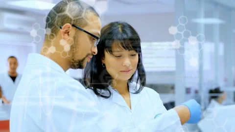Male lab scientist pointing at sample, female adjusting vial, hexagons Stock Footage 335235025
