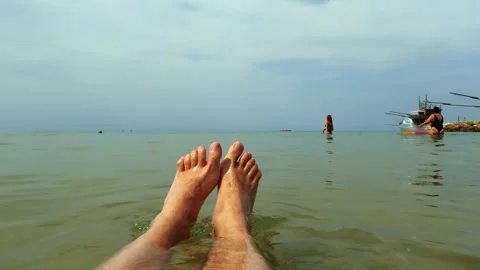 Male legs relaxing while floating on sea with people Stock Footage 280775286