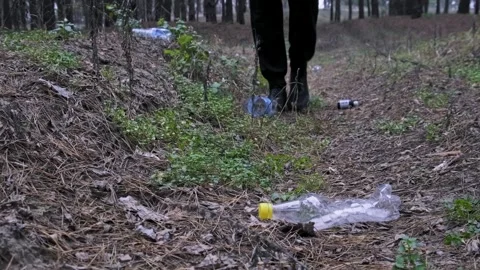 Male Legs Walking Through Garbage and Plastic Bottles in Forest Stock Footage 323316393