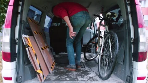 Male loader in red pulls box out trunk. Holds an object with his hands Video stock 149997300