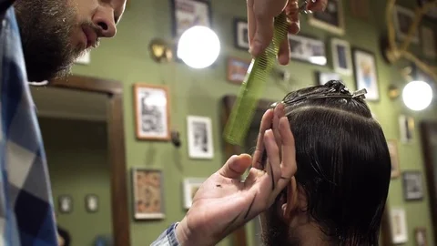 Male long haired barber combing and cutting hair of a male client Stock Footage 69960797