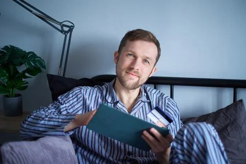 Male lying on bed using tablet for shopping on black friday with credit card Stock-Fotos