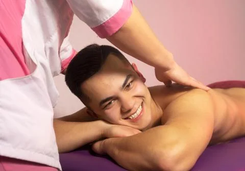Male lying down in a beauty and spa salon. Close up of hands doing back massa Stock Photos