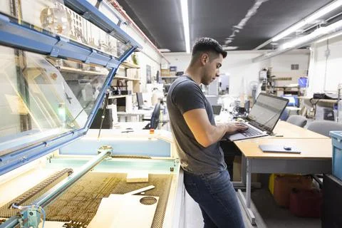 Male maker using laptop at 3D printer in workshop Foto stock