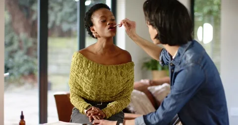 Male makeup artist at table selecting lip brush and applying lipstick on African Stock Footage 341932048