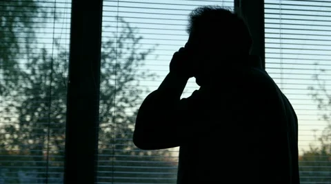 Male man looking out the window and makes an urgent call on the phone Stock Footage 64520118
