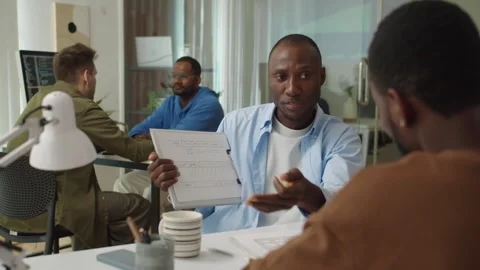 Male Manager Demonstrating Interface of Application on Paper to Another Employee Stock Footage 277413560