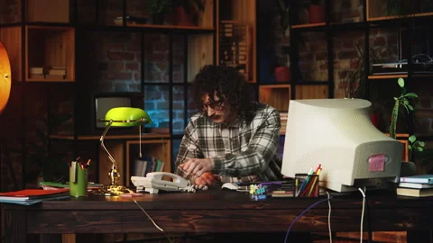 Male manager working on computer in 90s office, making landline phone call Stock Footage 321072434