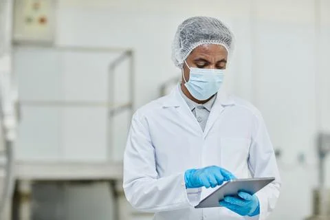 Male Manufacturing Supervisor Working Using Tablet at Pharmaceutical Factory 写真素材