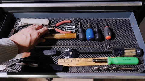 A male master opens a drawer with tools and takes a tape measure and a hammer Stock Footage 86986961