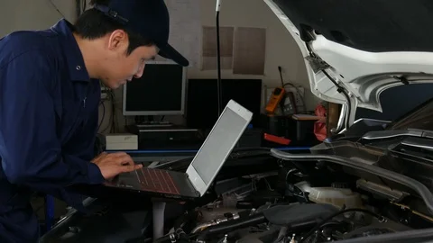 Male mechanic using a laptop while repairing car in auto service Video stock 130130183
