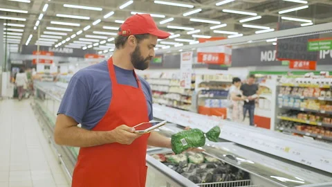 Male merchandiser in red uniform checking products with digital tablet Stock Footage 92737949