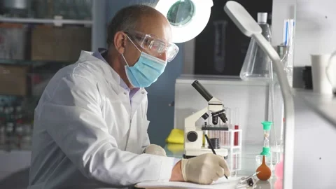 Male microbiologist make notes while analyzing the test tubes in lab. Stock Footage 145220683