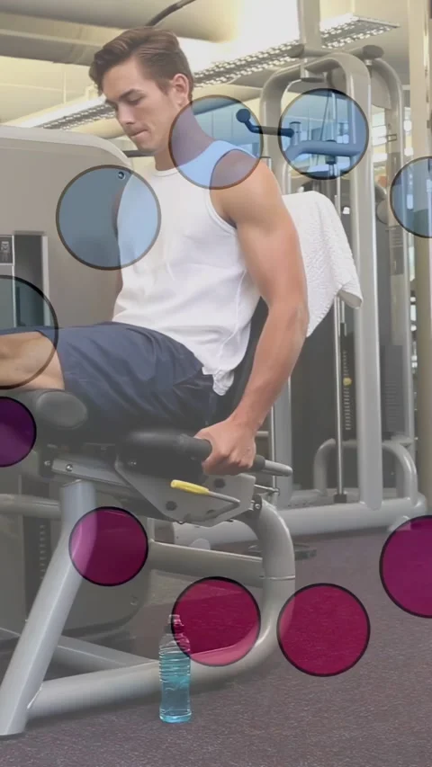 Male mid20s adjusting grip performing leg extensions on gym machine wearing Stock Footage 332707255
