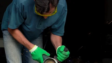 Male-middle-aged worker with angular grinding machine is cutting the metal Stock Footage
