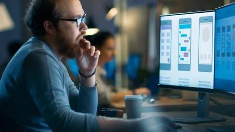Male Mobile Application Developer Works with Graphics on His Personal Compute Stockfoto's