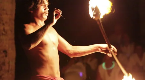 Male native fire dancer elaborately juggles a fire ring, throwing/catching Vidéo 68101384