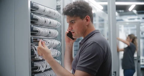 Male Network Engineer Auditing Server Connections While Talking on Smartphone Stock Footage 344968893