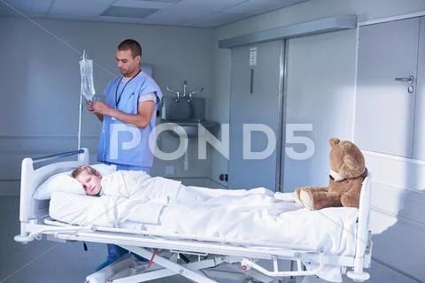 Male Nurse Adjusting Intravenous Drip For Boy Patient In Hospital Children's