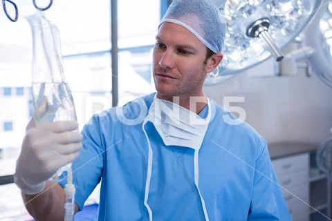 Male nurse adjusting iv drip in operation theater Stock Photos